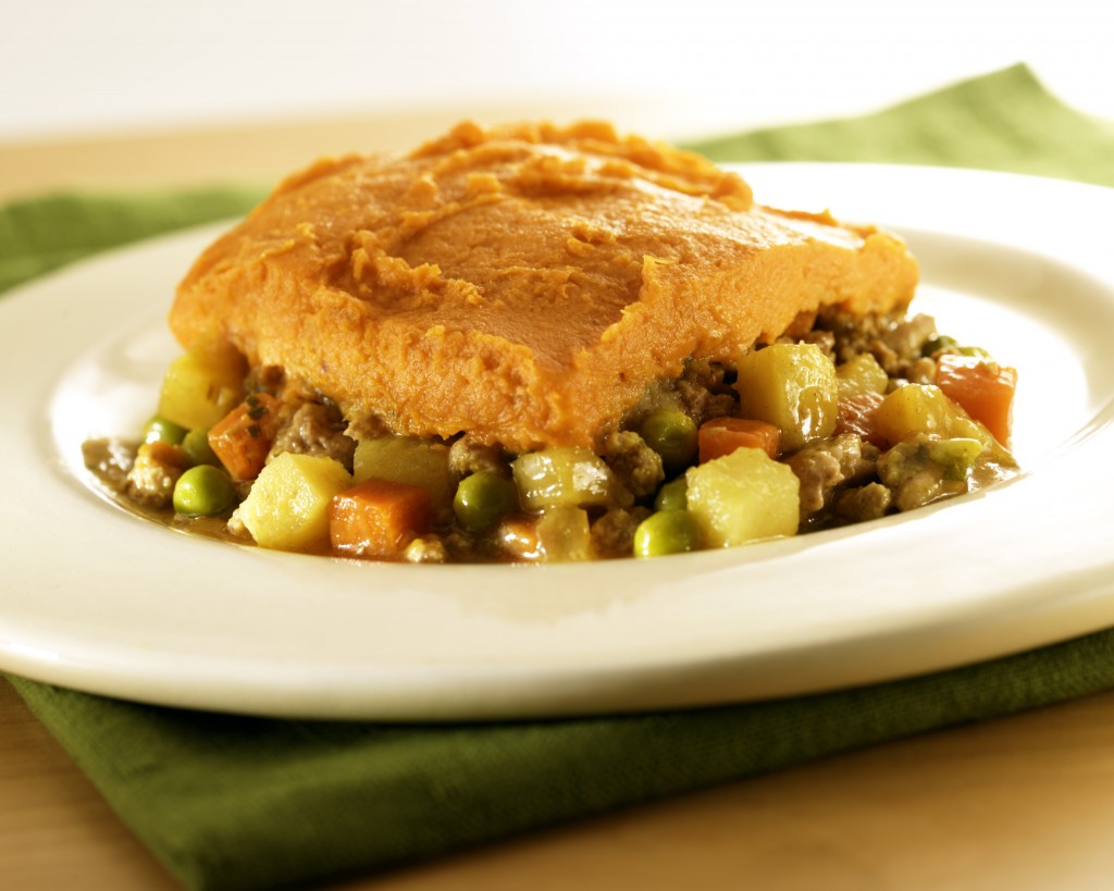 Hearty sheppard's pie slice with bosc pears on a white plate with a green napkin