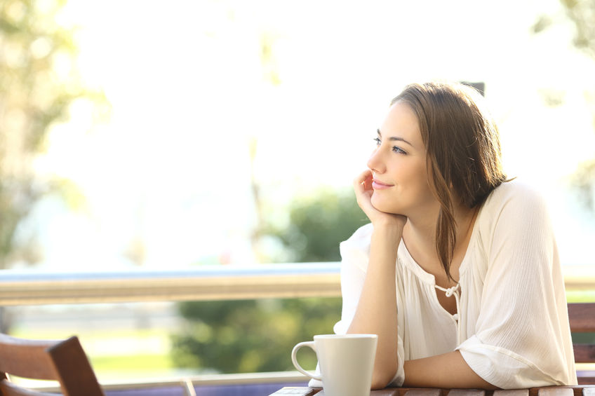 52549295 - pensive happy woman remembering looking at side sitting in a bar or home terrace