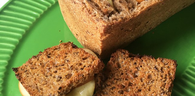 Little grilled cheese and pickled pear snadwiches stuffed inside a hollowed out bread loaf on a green plate